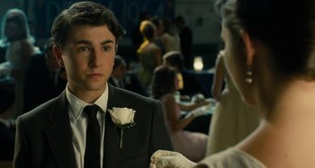 Movie still from “The Fabelmans” (2022), directed by Steven Spielberg – A young man wearing a suit and a white rose in his lapel; Close Up shot, Over the shoulder angle