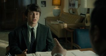 Movie still from “The Fabelmans” (2022), directed by Steven Spielberg – A man in a suit and tie sitting at a table; Medium shot, Over the shoulder angle