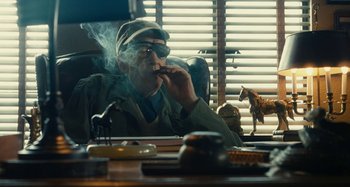 Movie still from “The Fabelmans” (2022), directed by Steven Spielberg – A man sitting at a desk smoking a pipe; Medium shot, Low angle