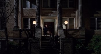 Movie still from “The Faculty” (1998), directed by Robert Rodriguez – A group of people standing on steps in front of a building at night; Extreme Wide shot, Low angle