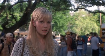 Movie still from “The Faculty” (1998), directed by Robert Rodriguez – A woman with long blonde hair standing in front of a crowd of onlookers; Close Up shot, Over the shoulder angle