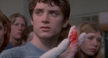 Movie still from “The Faculty” (1998), directed by Robert Rodriguez – A young man holding a piece of food in his hand; Close Up shot, Over the shoulder angle