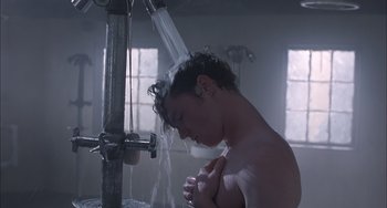 Movie still from “The Faculty” (1998), directed by Robert Rodriguez – A young man is taking a shower in a bathroom; Medium shot, Low angle