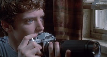 Movie still from “The Faculty” (1998), directed by Robert Rodriguez – A man holding a camera up to his face; Extreme Close Up shot, Over the shoulder angle