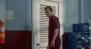 Movie still from “The Faculty” (1998), directed by Robert Rodriguez – A man standing in front of an open door; Medium shot, Low angle