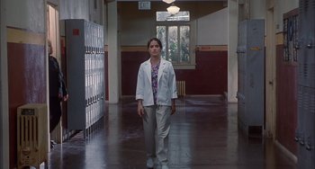 Movie still from “The Faculty” (1998), directed by Robert Rodriguez – A woman in a white lab coat walking down a hall way; Wide shot, Low angle