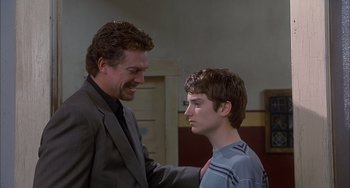 Movie still from “The Faculty” (1998), directed by Robert Rodriguez – A man in a suit and a young man in a blue shirt; Medium shot, Over the shoulder angle