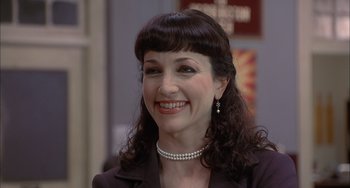 Movie still from “The Faculty” (1998), directed by Robert Rodriguez – A person wearing a suit and a pearl necklace; Close Up shot, Low angle