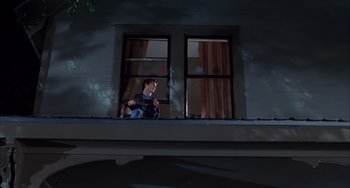Movie still from “The Faculty” (1998), directed by Robert Rodriguez – A man sitting on a window ledge looking out a window; Wide shot, Low angle