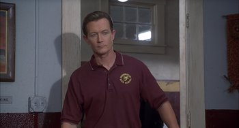 Movie still from “The Faculty” (1998), directed by Robert Rodriguez – A man in a maroon shirt standing in front of a window; Close Up shot, Over the shoulder angle