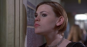 Movie still from “The Faculty” (1998), directed by Robert Rodriguez – A woman with short brown hair wearing a necklace looking into a mirror; Close Up shot, Low angle