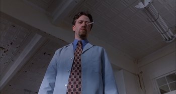 Movie still from “The Faculty” (1998), directed by Robert Rodriguez – A man in a blue suit and a brown and blue neck tie; Medium shot, Low angle