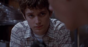 Movie still from “The Faculty” (1998), directed by Robert Rodriguez – A young man looking at the camera while holding a cell phone; Close Up shot, Over the shoulder angle