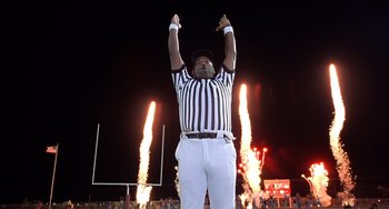 Movie still from “The Faculty” (1998), directed by Robert Rodriguez – A football referee holding his hands up in the air; Medium shot, Low angle