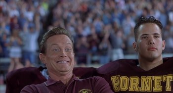 Movie still from “The Faculty” (1998), directed by Robert Rodriguez – A man sitting in front of a crowd of people; Close Up shot, Low angle