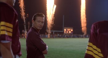 Movie still from “The Faculty” (1998), directed by Robert Rodriguez – A man standing on a field with arms crossed; Medium shot, Over the shoulder angle