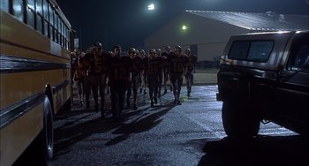 Movie still from “The Faculty” (1998), directed by Robert Rodriguez – A group of football players are walking in the rain; Wide shot, Low angle