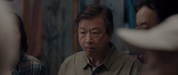 Movie still from “The Farewell” (2019), directed by Lulu Wang – An older asian man looking at the camera; Close Up shot, Over the shoulder angle