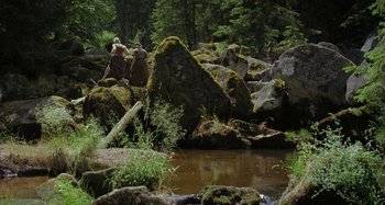 Movie still from “The Field Guide to Evil” (2018), directed by Can Evrenol – A group of people standing next to a stream; Extreme Wide shot, High angle