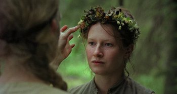 Movie still from “The Field Guide to Evil” (2018), directed by Can Evrenol – A woman wearing a wreath of flowers on her head looking at a man; Close Up shot, Over the shoulder angle
