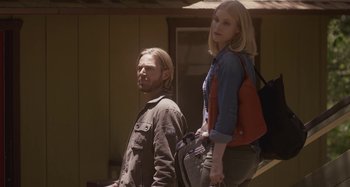 Movie still from “The Field Guide to Evil” (2018), directed by Can Evrenol – A man and a woman standing next to each other in front of a building; Medium shot, Low angle