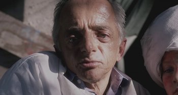 Movie still from “The Field Guide to Evil” (2018), directed by Can Evrenol – An older man with gray hair is looking at the camera; Close Up shot, Low angle