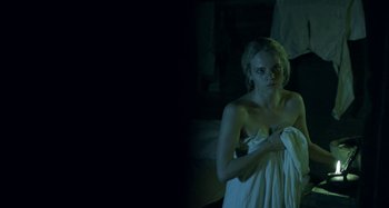Movie still from “The Field Guide to Evil” (2018), directed by Can Evrenol – A woman wrapped in a towel in a dark room; Medium shot, Low angle