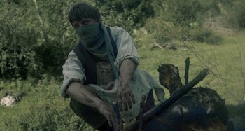 Movie still from “The Field Guide to Evil” (2018), directed by Can Evrenol – A man wearing a bandanna and holding a knife; Medium shot, High angle