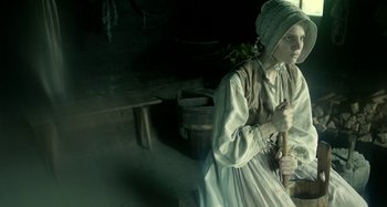 Movie still from “The Field Guide to Evil” (2018), directed by Can Evrenol – A woman dressed in old fashion clothing holding a stick; Medium shot, High angle
