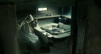 Movie still from “The Field Guide to Evil” (2018), directed by Can Evrenol – A woman sitting on a bench in a room; Wide shot, High angle