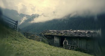 Movie still from “The Field Guide to Evil” (2018), directed by Can Evrenol – A man standing in front of an old cabin; Extreme Wide shot, High angle