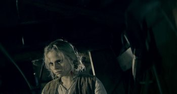 Movie still from “The Field Guide to Evil” (2018), directed by Can Evrenol – A young woman with blonde long hair wearing a white shirt; Close Up shot, High angle
