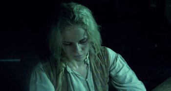 Movie still from “The Field Guide to Evil” (2018), directed by Can Evrenol – A woman with long blonde hair sitting in the dark; Close Up shot, High angle