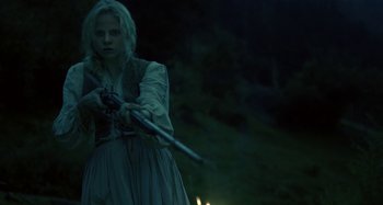 Movie still from “The Field Guide to Evil” (2018), directed by Can Evrenol – A woman holding a pair of swords while standing in the dark; Medium shot, Low angle