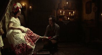 Movie still from “The Field Guide to Evil” (2018), directed by Can Evrenol – A man sitting on the floor in front of candles; Wide shot, Low angle