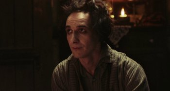 Movie still from “The Field Guide to Evil” (2018), directed by Can Evrenol – A man sitting in front of a fireplace; Close Up shot, Low angle