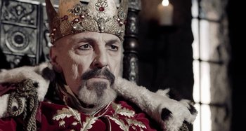 Movie still from “The Field Guide to Evil” (2018), directed by Can Evrenol – A man with a beard wearing a crown; Close Up shot, Low angle