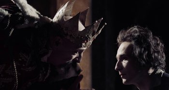 Movie still from “The Field Guide to Evil” (2018), directed by Can Evrenol – Two people are facing each other with a crown on their head; Close Up shot, Over the shoulder angle