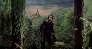 Movie still from “The Field Guide to Evil” (2018), directed by Can Evrenol – A man with a mask is standing in the woods; Wide shot, Low angle