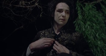 Movie still from “The Field Guide to Evil” (2018), directed by Can Evrenol – A man in a black and gold outfit fixing his tie; Medium shot, Low angle