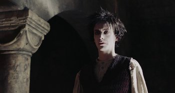 Movie still from “The Field Guide to Evil” (2018), directed by Can Evrenol – A young man in a black vest is looking at the camera; Close Up shot, Low angle