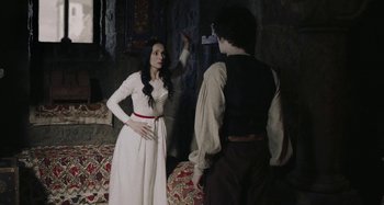 Movie still from “The Field Guide to Evil” (2018), directed by Can Evrenol – A woman in a white dress standing next to a man in a black shirt; Medium shot, Over the shoulder angle