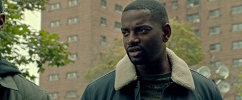 Movie still from “The First Purge” (2018), directed by Gerard McMurray – A person wearing a jacket; Close Up shot, Over the shoulder angle