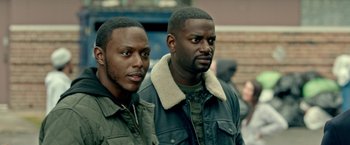 Movie still from “The First Purge” (2018), directed by Gerard McMurray – Two men standing next to each other on the street; Close Up shot, Over the shoulder angle