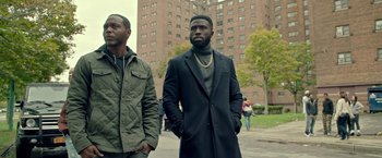 Movie still from “The First Purge” (2018), directed by Gerard McMurray – Two men standing next to each other on the sidewalk; Medium shot, Over the shoulder angle