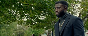Movie still from “The First Purge” (2018), directed by Gerard McMurray – A man in a black jacket and a gold chain necklace; Close Up shot, Over the shoulder angle