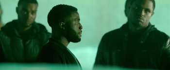 Movie still from “The First Purge” (2018), directed by Gerard McMurray – A man with a beard is looking into the distance; Medium shot, Over the shoulder angle