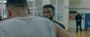 Movie still from “The First Purge” (2018), directed by Gerard McMurray – A man looking at another man in a gym; Close Up shot, Over the shoulder angle