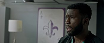 Movie still from “The First Purge” (2018), directed by Gerard McMurray – A person in a room near a painting; Close Up shot, Over the shoulder angle