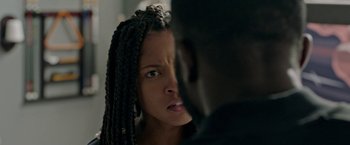Movie still from “The First Purge” (2018), directed by Gerard McMurray – A young woman with long braids looking at the camera; Close Up shot, Over the shoulder angle